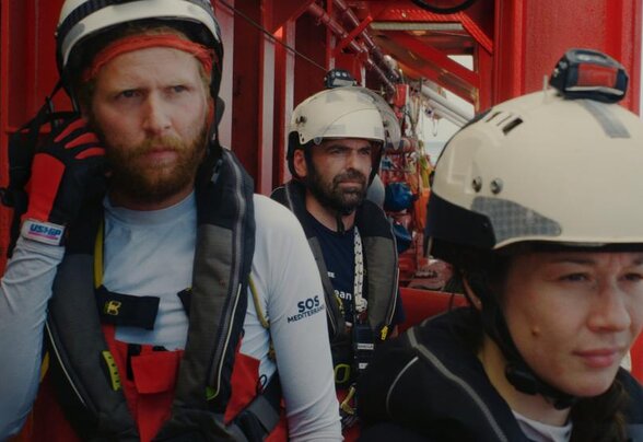 Trois membres d'équipage de l'Ocean Viking en gilets de sauvetage et casques blancs, à bord du navire SOS Méditerranée - Agrandir l'image, fenêtre modale